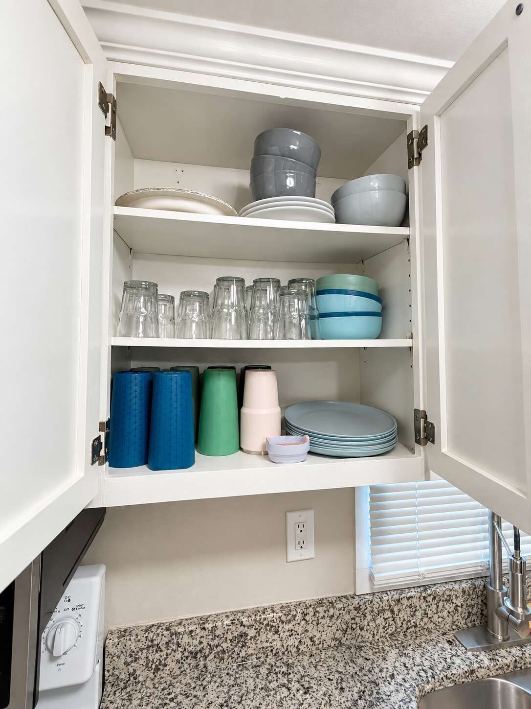 Una cocina con armarios blancos, encimera de granito y pileta de acero inoxidable.