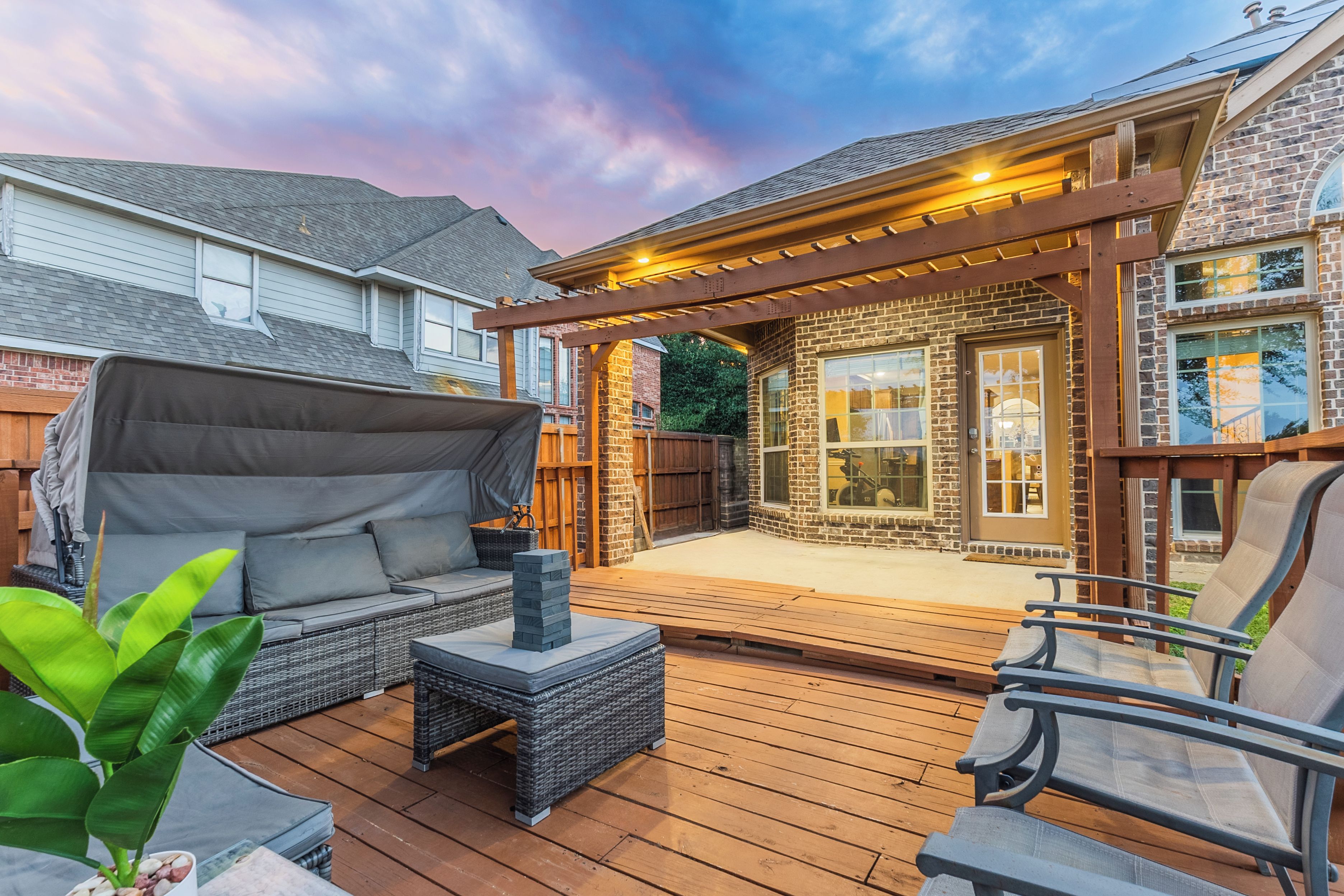 A covered outdoor seating area with a pergola, a covered sofa, and a small table.