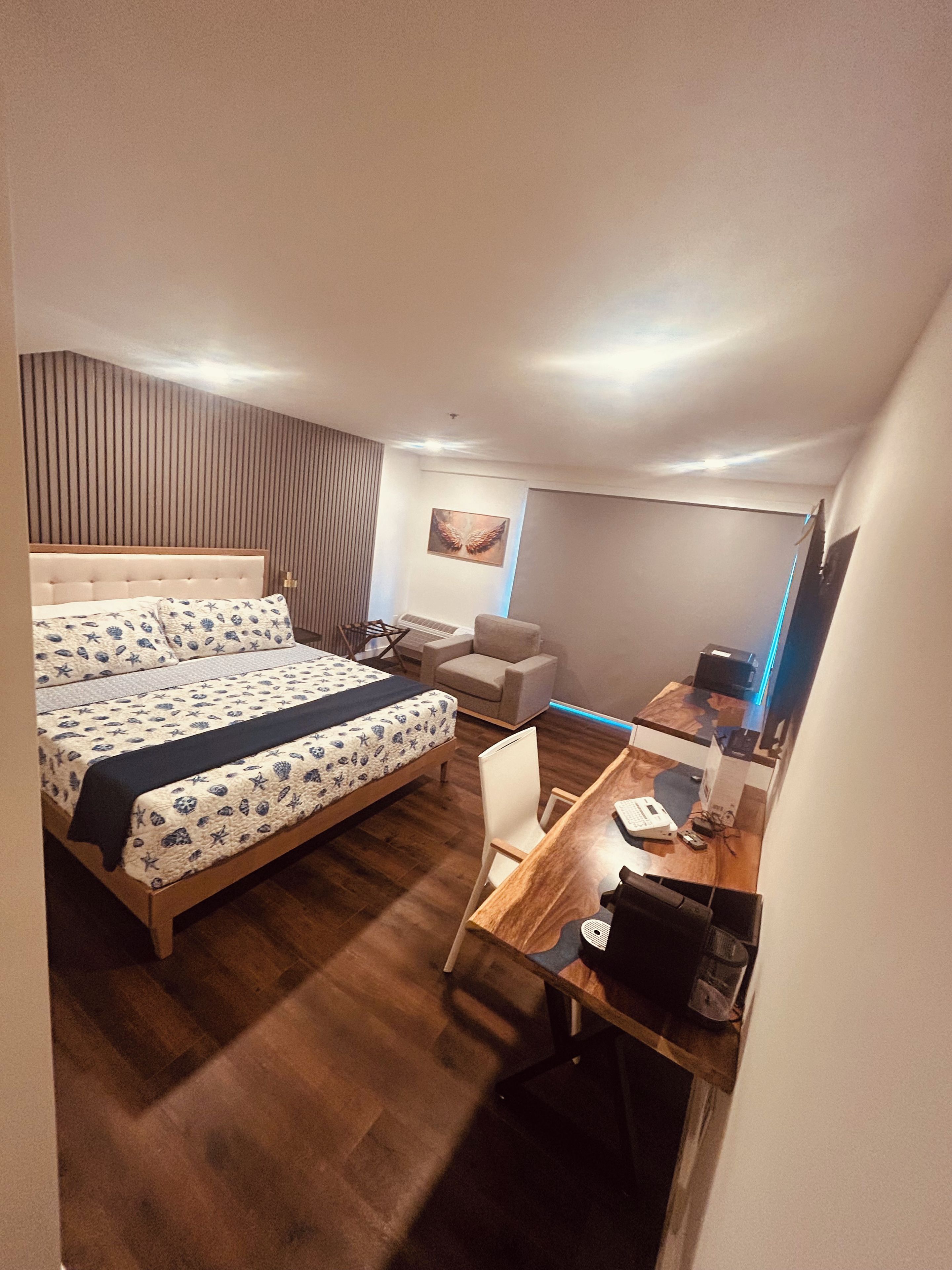 Un dormitorio con cama, escritorio, silla, radiador y televisor montado en la pared.