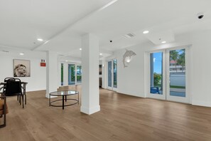Una habitació àmplia amb un sòl de fusta, una taula de vidre i un quadre al mur.