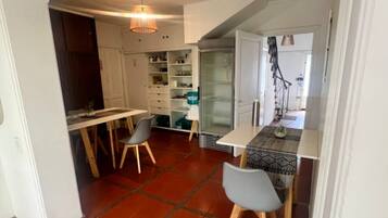 Eine kompakte Küche mit einem Fischgrätparkett, einem Essbereich mit zwei Stühlen und einem Einbauschrank mit Glastüren.