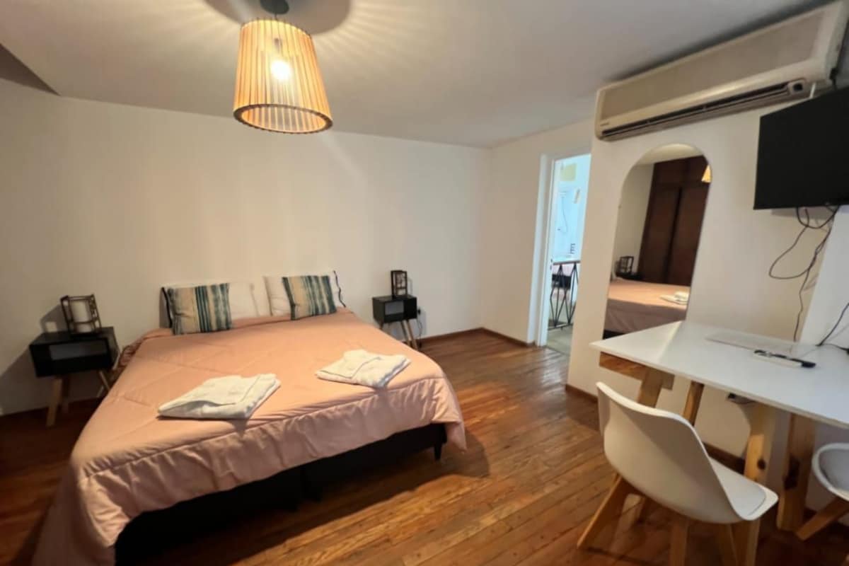 A bedroom with a bed, bedside tables, a desk, and a chair.