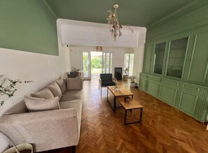 A spacious living room with a herringbone floor, a sofa set, a coffee table, and a green cabinet. - Casa Oliva B&B (Mendoza)
