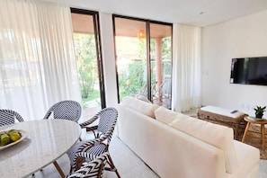 A modern living room with a sofa, chairs, a dining table, and a TV mounted on the wall. - vila Anambe (Ilhéus)