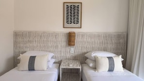 A hotel room with two beds, a small bedside table, and a decorative wall panel. - vila Anambe (Ilhéus)