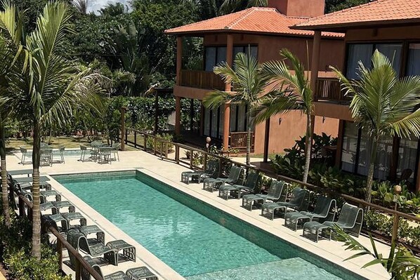 A pool area with lounge chairs and a building with a red roof.