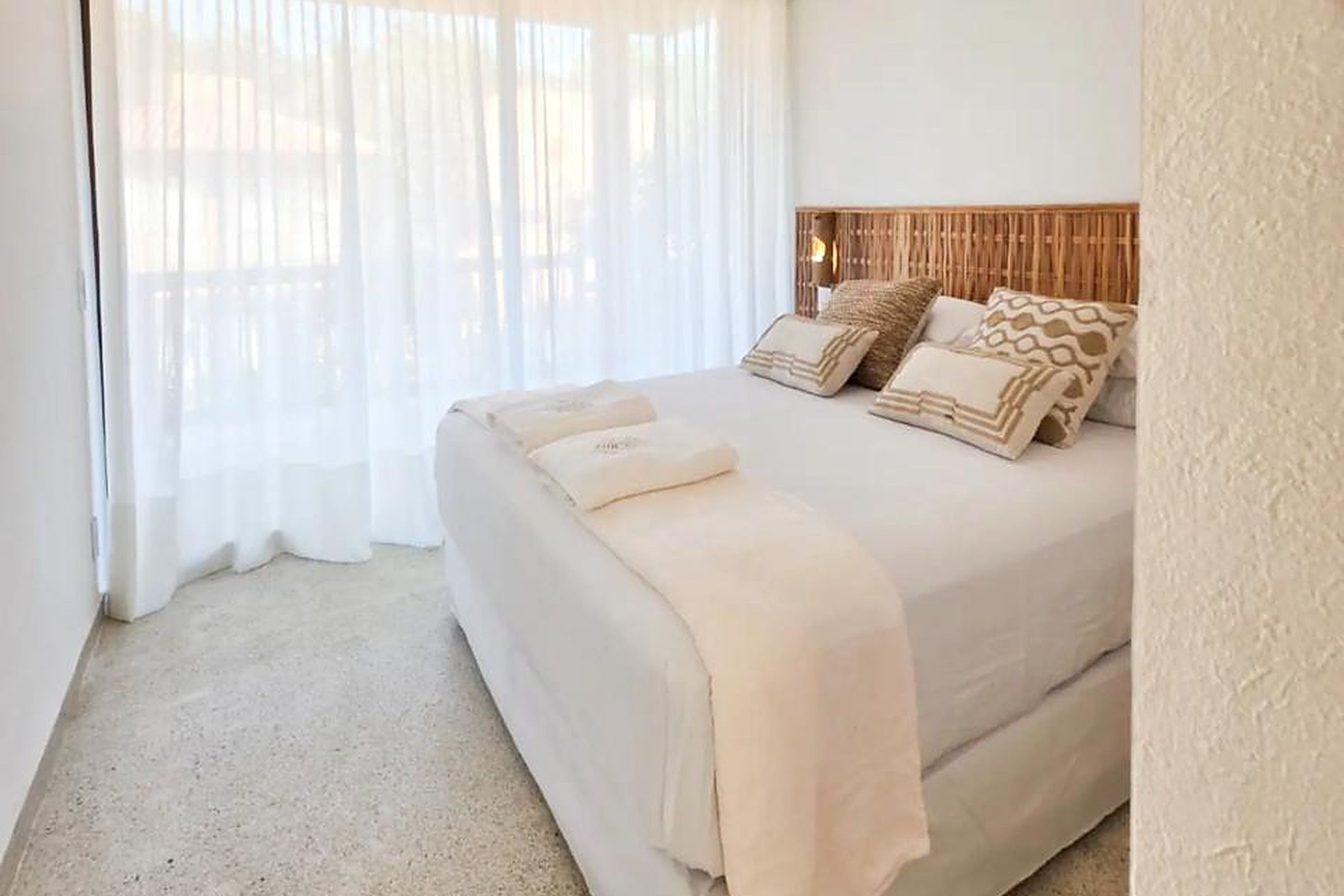Un dormitorio con cama, cortinas y cabecera.