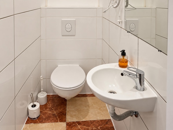 A bathroom with a toilet, sink, and mirror. - Your Vienna Routine 1BR and Living Room (Vienna)