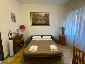 A bedroom with a bed, a bedside table, a lamp, a bookshelf, and a painting on the wall. - Yes Rome Holidays - One Bedroom Apartment, Sleeps 5 (Rome)