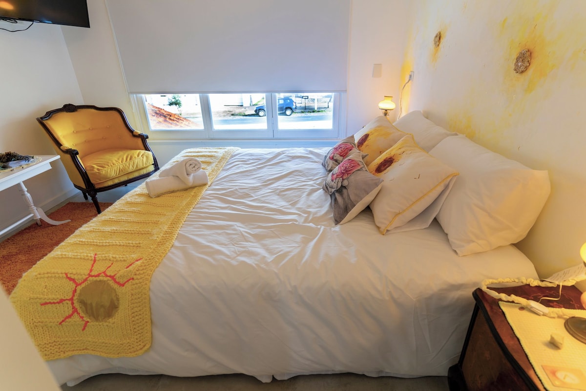 Een hotelkamer met een bed, een stoel, een bureau en een raam met uitzicht.