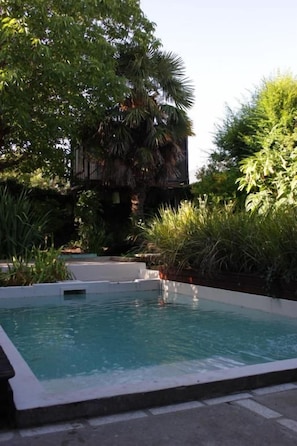 A swimming pool with a surrounding garden and a building in the background. - Allegra Dalila Casa Hotel-Arte (Tandil)
