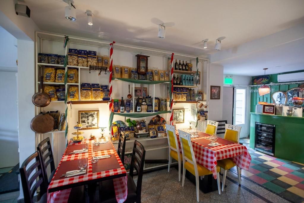 A restaurant with a checkered tablecloth, shelves stocked with food items, and a green counter area.