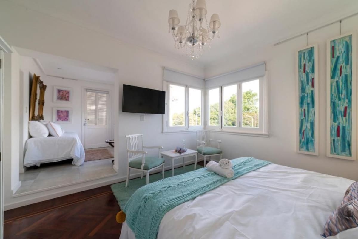 Een slaapkamer met een bed, een televisie, een raam en een stoel.