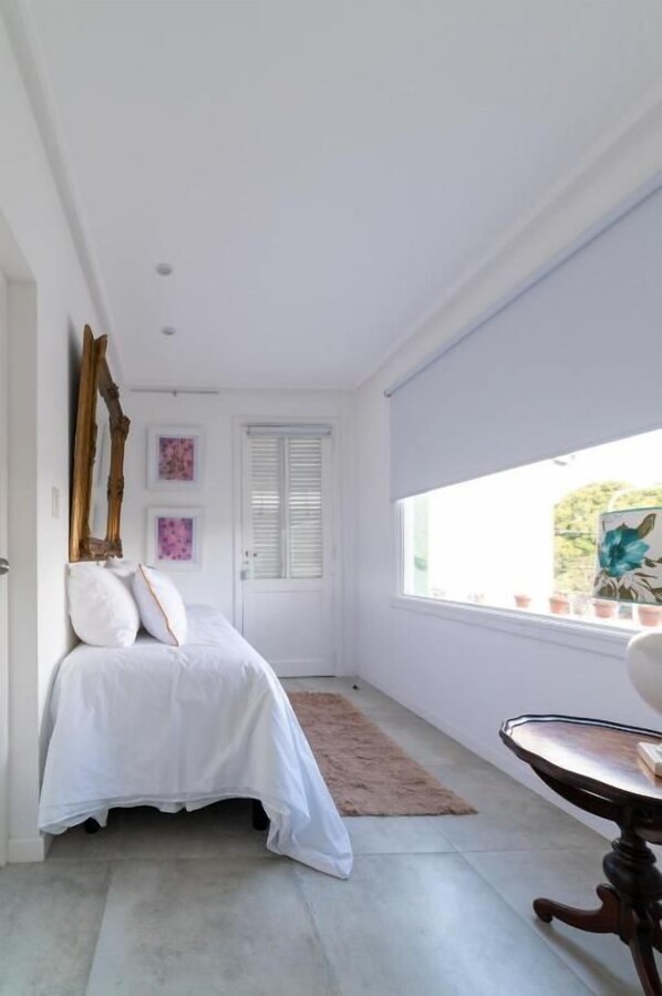 A bedroom with a bed, a window, a door, and a chair.