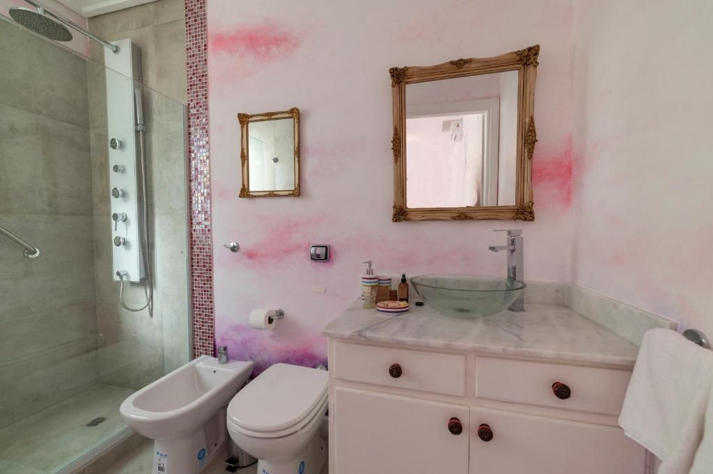 A bathroom with a shower, toilet, vanity, and two mirrors.