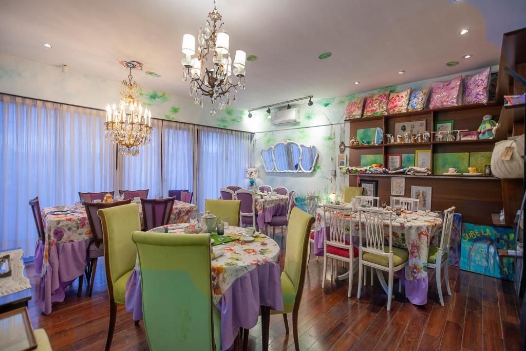 A dining area with round tables, chairs, and a chandelier.