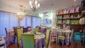 A dining area with round tables, chairs, and a chandelier.
