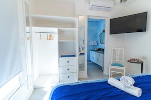 A bedroom with a bed, a wardrobe, a desk, and a television.