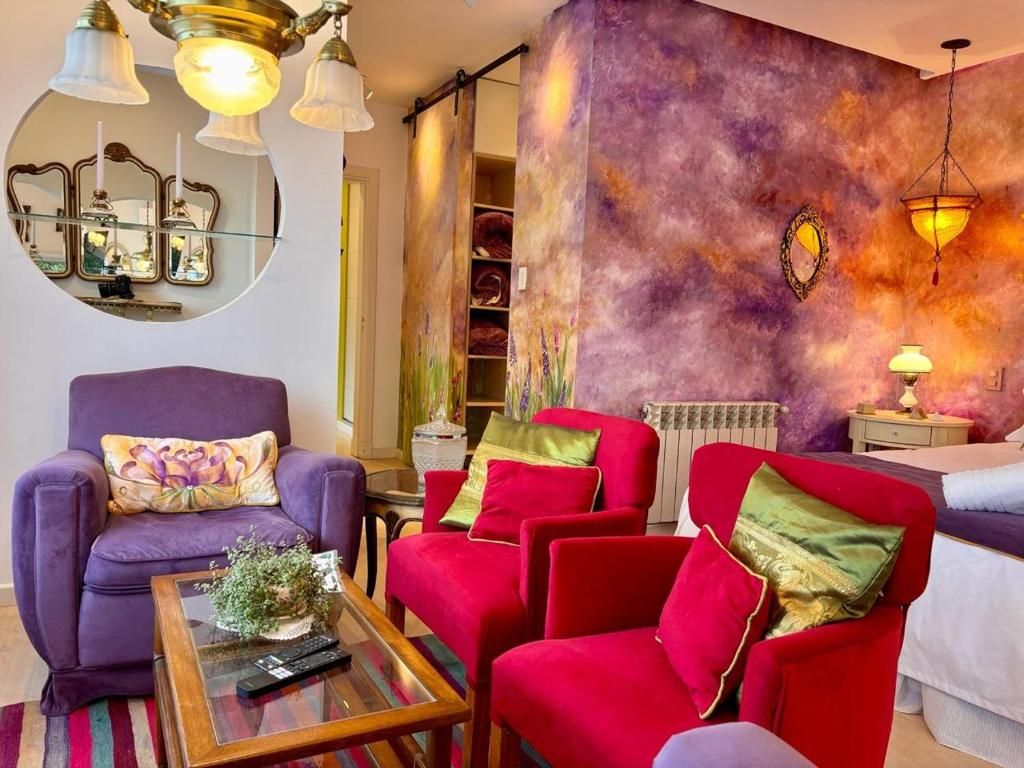 A living room with a purple armchair, red armchairs, and a coffee table.