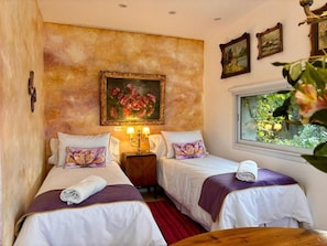 Habitación de hotel con dos camas, un cuadro en la pared y una ventana con vistas a zonas verdes.