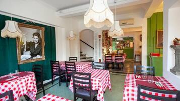 A restaurant with checkered tablecloths, hanging lamps, and a staircase leading to a bar area.