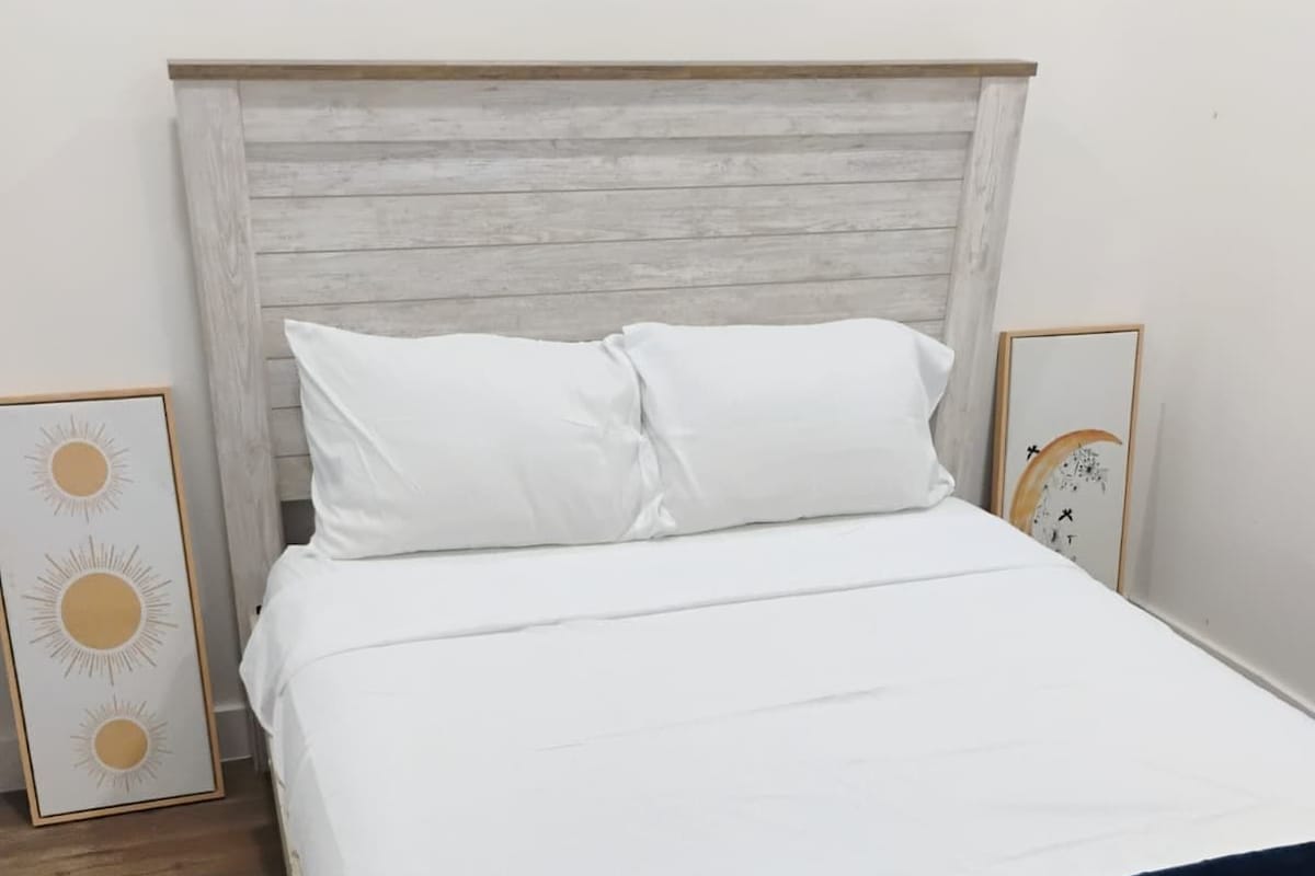 A bed with a wooden headboard, white bedding, and a dark blue throw blanket.