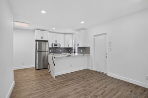 A modern kitchen with white cabinetry, a stainless steel refrigerator, a microwave, and a sink. - 1946 Pierce Street (Hollywood)