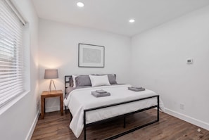 A modern bedroom with a bed, bedside table, lamp, and a framed picture on the wall. - 1946 Pierce Street (Hollywood)