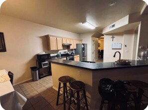 Una cocina con una isla central, taburetes de bar y un lavabo.