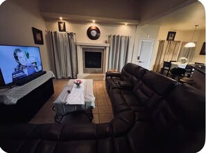 Una sala de estar con sofá, una mesa de centro, chimenea, televisor y un comedor con mesa y sillas.