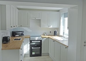A compact kitchen with white cabinets, a toaster, a kettle, and a stove. - A beautifully restored two-storey, two bedroom cottage sleeping four people. (Filey)