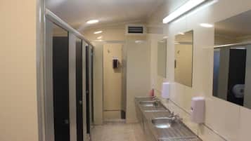 Un baño de hotel con varios lavamanos, un secador de manos y un espejo.
