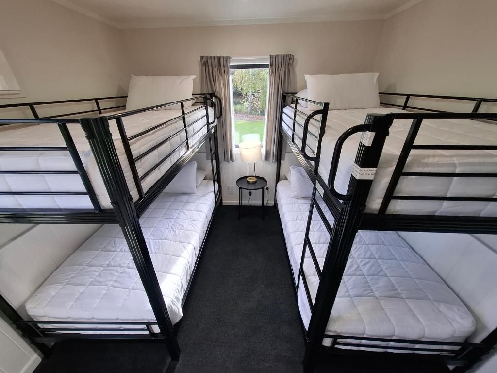 Una habitación con literas, una mesita pequeña y una ventana con cortinas.