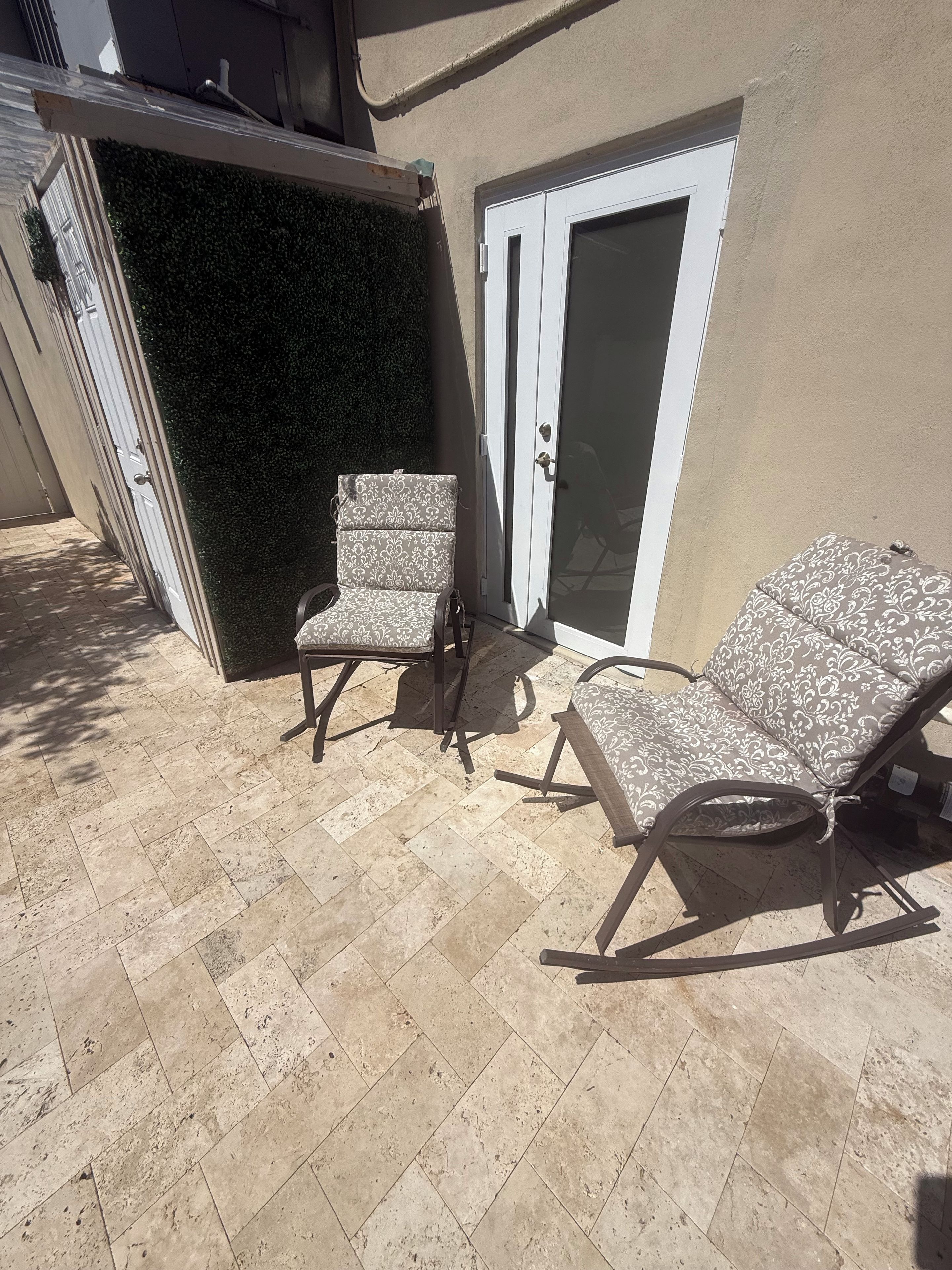 A patio area with two lounge chairs and a door.