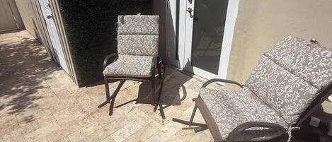 A patio area with two lounge chairs and a door.