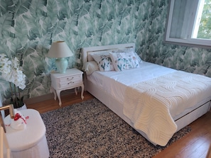 Ein Schlafzimmer mit Bett, Nachttisch, Lampe und dekorativen Kissen.