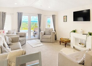 A spacious living room with a fireplace, comfortable seating, and a television. - 2 bedroom accommodation in Colyton (Colyton)