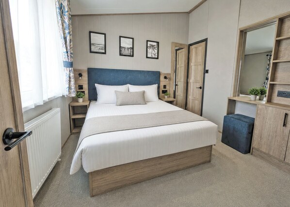 Ein Schlafzimmer mit einem Bett, Nachttischen, einem Kleiderschrank und einem Spiegel.