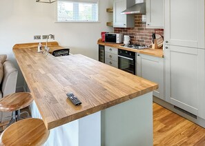 Eine moderne Küche mit einer Holzinsel, Barhocker, einer Mikrowelle und einem Gasherd.