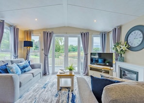 Een woonkamer met een bank, een salontafel, een televisie en een open haard.