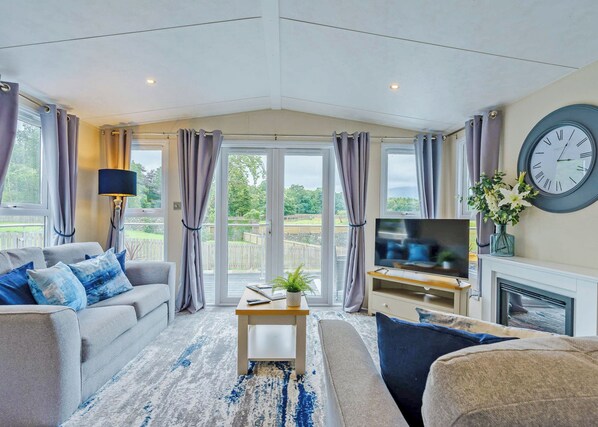 A living room with a sofa, a coffee table, a TV, and a fireplace. - Premium 2 bed holiday home with hot tub Pet (Bassenthwaite, near Keswick)