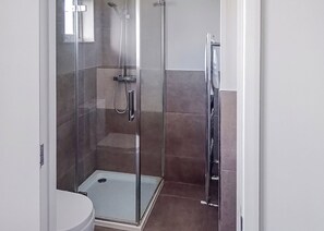 A glass-enclosed shower stall with a handheld showerhead, a wall-mounted faucet, and a step into the shower. - Elite Spa Lodge 3 (3 Doubles) (Newbury)
