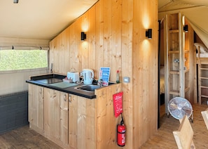 A compact kitchen with wooden walls, a sink, a toaster, a kettle, and a fire extinguisher. - Sea View Safari Tents (Hemsby)