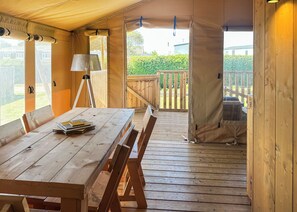 Una terraza de madera con una mesa, sillas, una lámpara y vistas a un jardín.