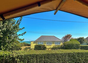 A house with a grey roof, surrounded by greenery and a clear blue sky. - Sea View Safari Tents (Hemsby)