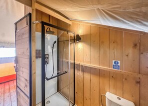 A wooden-paneled bathroom with a glass-enclosed shower, a toilet, and a towel rack. - Safari Tent - Pet Friendly (Hemsby)