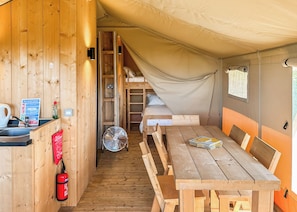 A tent with a bunk bed, a table with chairs, a fan, and a fire extinguisher. - Safari Tent - Pet Friendly (Hemsby)