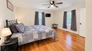 A bedroom with a bed, a nightstand, a lamp, a ceiling fan, and a TV on the wall. - Lick Creek Pit Stop   
Dog friendly  
Direct trail access 
2 Kings 2 Queens (Williamson)