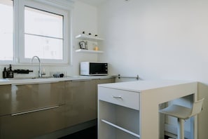A modern kitchen with a microwave, sink, and a small window. - 3-Bedroom House with Garden (Liège)