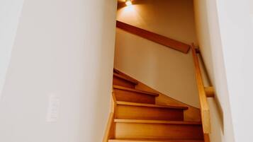Un escalier en bois, doté d’une rampe et d’un luminaire fixé au mur.
